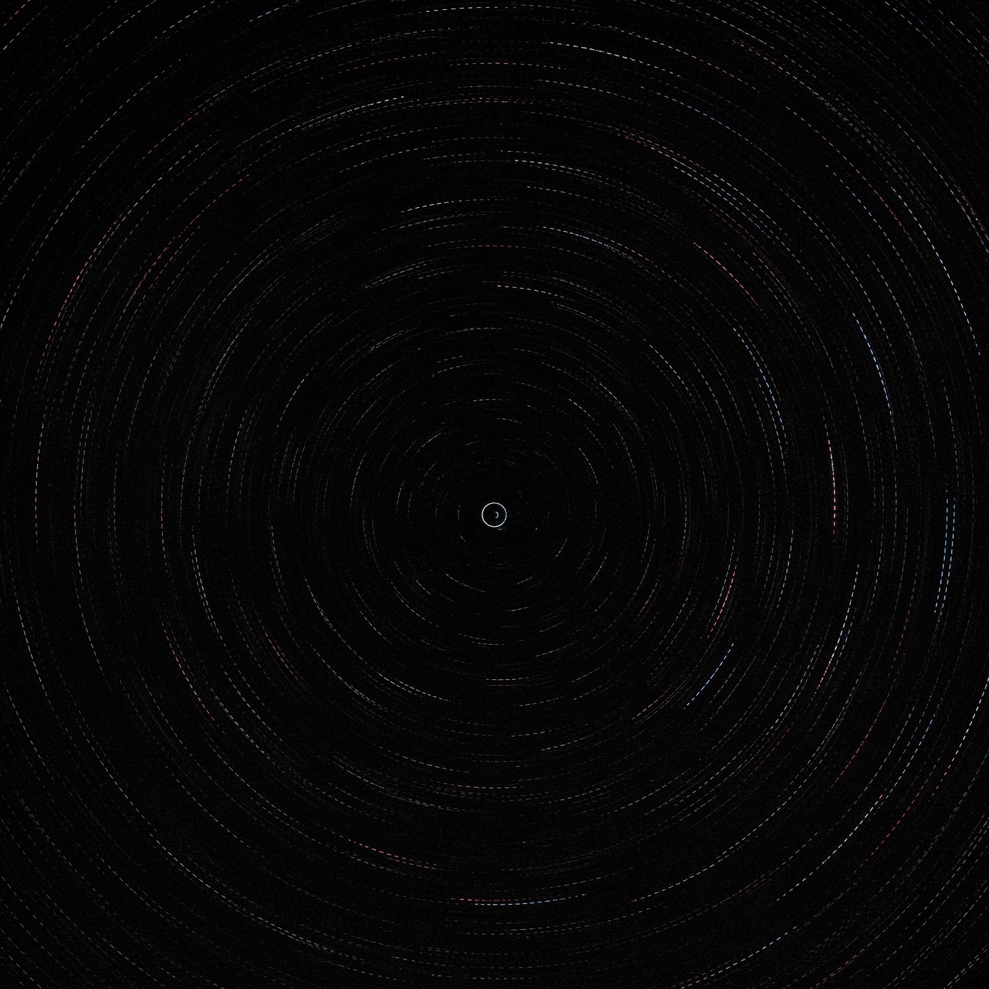 Long red and blue arcs across a black sky. One star near the center draws only a tight circle.
